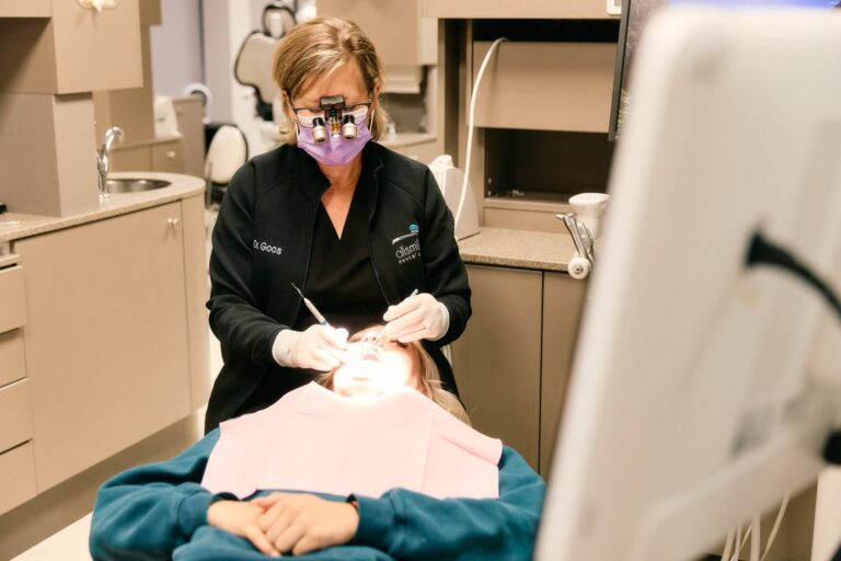 Dentist performing treatment wearing loupes on patient